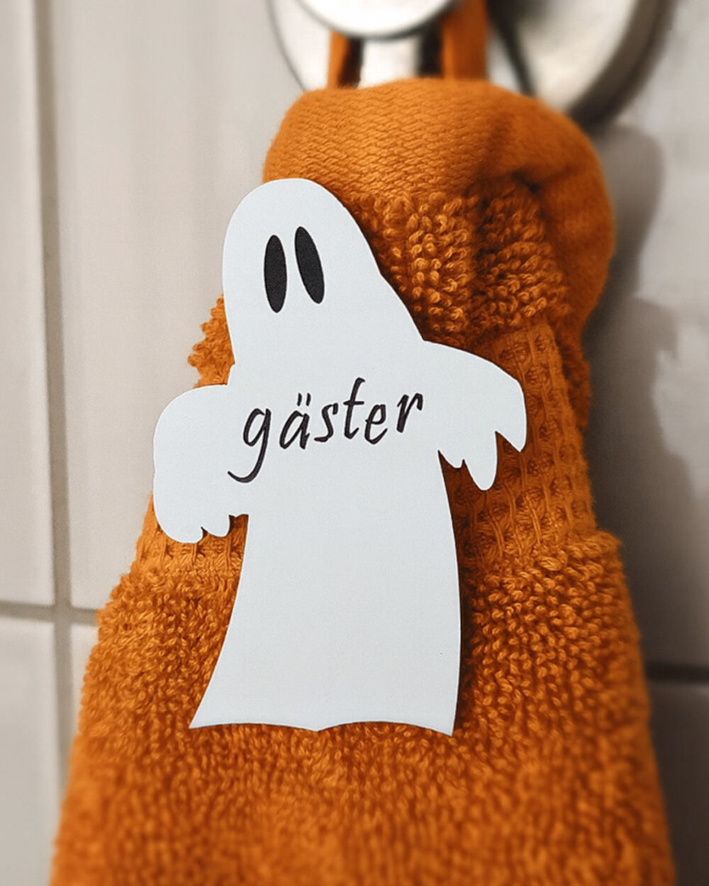 vitt spöke med texten gäster ingraverat i svart. Sitter på orange gästhandduk. Hygienisk och dekorativt till Halloween