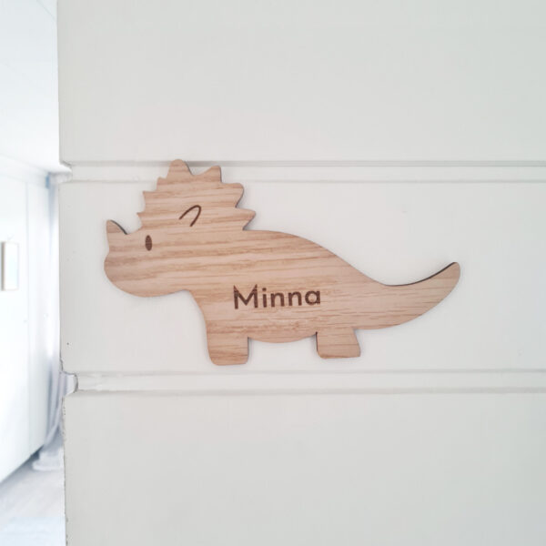 dino, tricertops dörrskylt till barnrum. vit vägg och vit dörr
